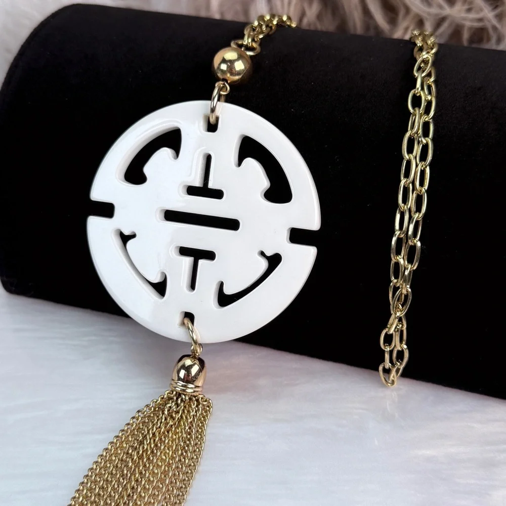 Long, goldtone, costume necklace, with large white pendant, and metal fringe
